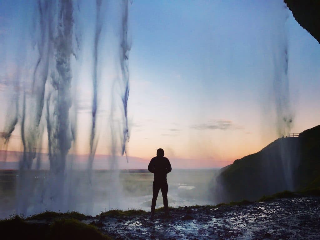 Standing under a waterfall in Iceland at sunset