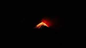 a lava eruption from a cone structured volcano at night