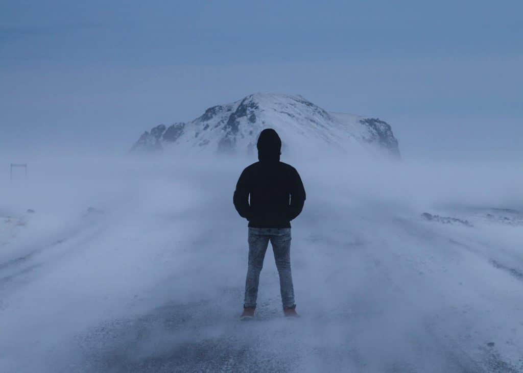 A person standing in bad weather in Iceland on a snow-covered road
