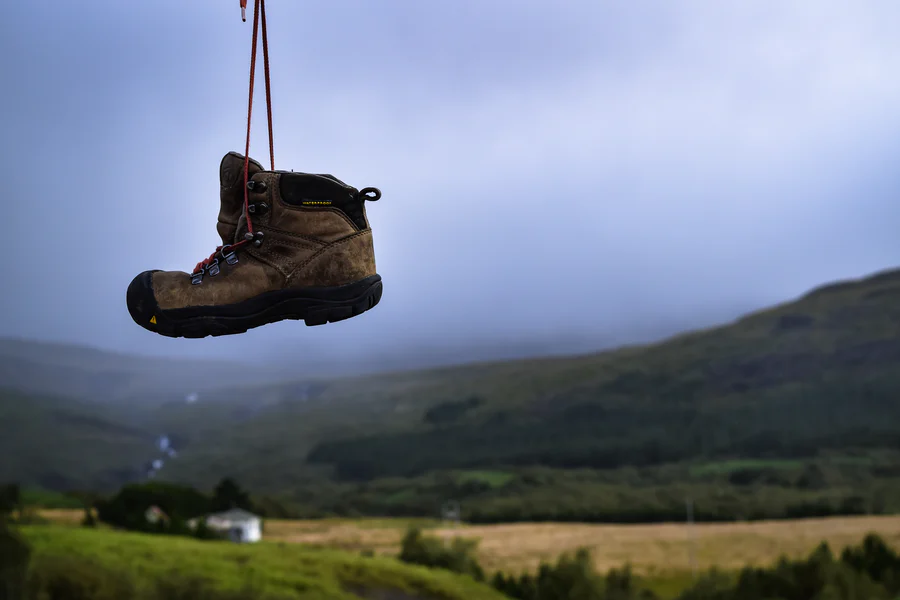 Hiking Boots strung up against a background of mist-covered mountains