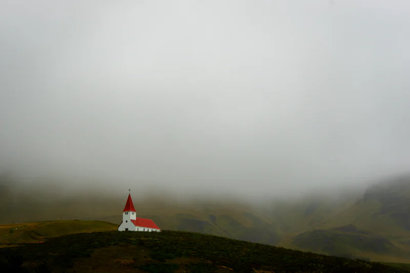 Vík church in south Iceland with a backdrop of mist-covered mountains