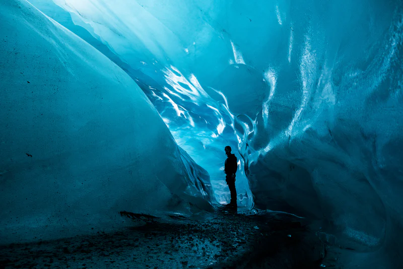A man standing in a blue ice cave in Iceland